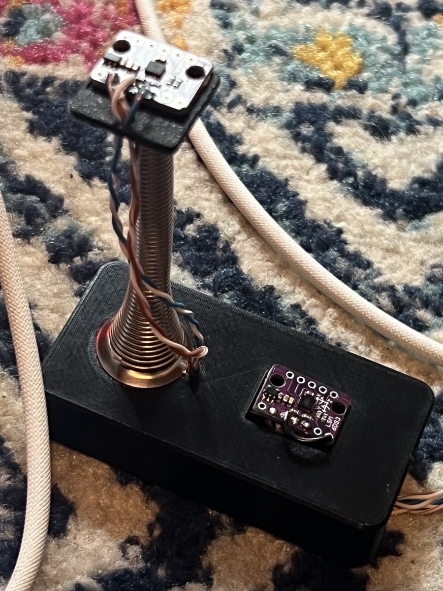 The boing pedal prototype: a black box with a doorstop spring sticking out of it, a small circuit board on top of the spring